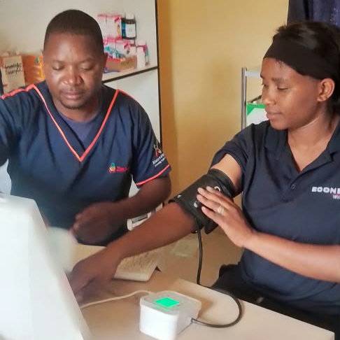 ZimSmart Villages nurses taking a patient's blood pressure at a telehealth kiosk